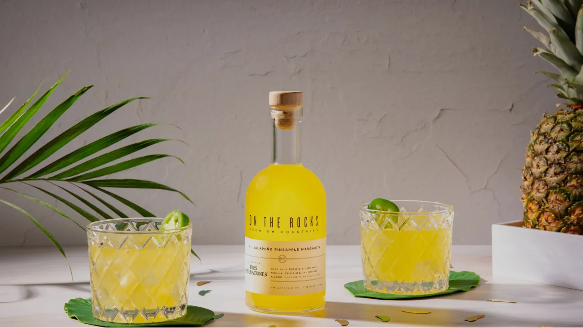 image of OTR -Jalapeno Pineapple Margarita bottle and filled cocktail glasses placed on table
