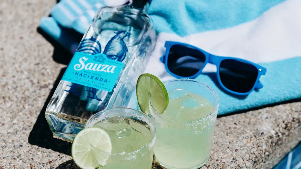 image of Sauza Hacienda bottle lying in sand besides sunglasses
